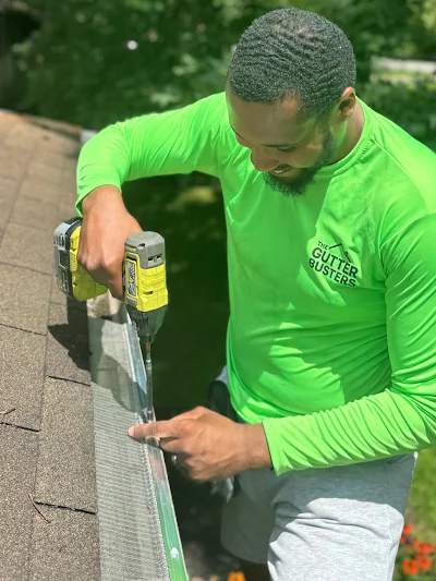 The Gutter Busters technician installing a gutter guard on a Cleveland home roof